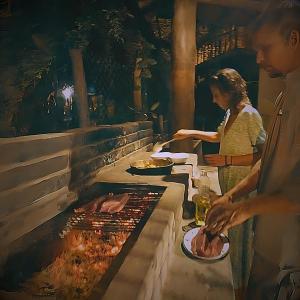 paru ludzi gotujących jedzenie na grillu w obiekcie Las Chelitas Casa del Mar - Nueva Administración de Maru Mar w mieście Popoyo