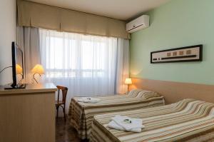 a hotel room with two beds and a desk at Hotel Sinuelo in Jaguarão +22 photos