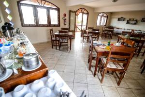 uma sala de jantar com mesas, cadeiras e janelas em Pousada Tranquilandia Village em Canoa Quebrada