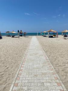 a brick walkway on a beach with umbrellas at Pines Paradise at Blue Laguna Residence in Golem
