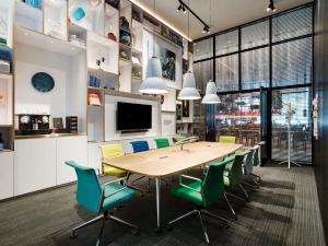 a conference room with a wooden table and green chairs at citizenM Miami South Beach in Miami Beach