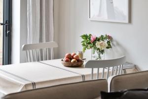 einen Tisch mit einer Schale Obst und einer Vase Blumen in der Unterkunft Cotswold Luxury Coach House - ideal for couples, w/ EV charging in Andoversford