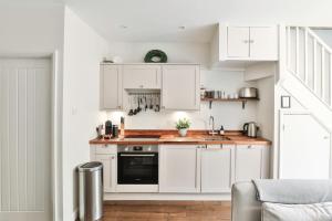 eine Küche mit weißen Schränken und einem schwarzen Backofen in der Unterkunft Cotswold Luxury Coach House - ideal for couples, w/ EV charging in Andoversford