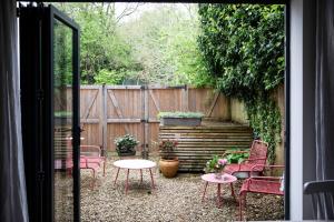 eine Terrasse mit Stühlen, einem Tisch und einem Zaun in der Unterkunft Cotswold Luxury Coach House - ideal for couples, w/ EV charging in Andoversford + 24 Fotos