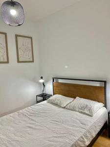 a bedroom with a white bed with a wooden headboard at Valleca Tren Sierra Guadalupe 2 in Madrid