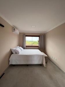 um quarto com uma cama grande e uma janela em Chalé do Bosque Corumbau em Prado