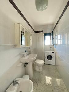 a bathroom with a sink and a toilet and a washing machine at Casa Efesto - Piano terra, fronte spiaggia in Marina di Pescoluse