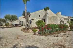 a large stone house with palm trees and flowers at Casale Arezzo - Luxury Villa With Pool & Jacuzzi - Marina di Ragusa in Ragusa