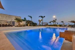 a swimming pool with blue water in a resort at Casale Arezzo - Luxury Villa With Pool & Jacuzzi - Marina di Ragusa in Ragusa
