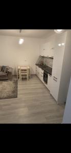 Il comprend une cuisine avec des placards blancs et du parquet. dans l'établissement one bedroom apartment, à Tirana