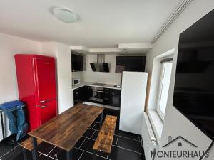 eine Küche mit einem roten Kühlschrank und einem Holztisch in der Unterkunft Monteurhaus in Unterkirchberg