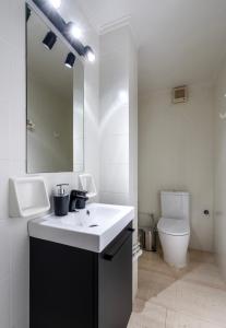 a white bathroom with a sink and a toilet at SummerVibes Penthouse Varkiza in Vari