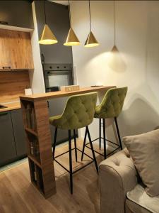 une cuisine avec une table et deux chaises vertes dans l'établissement Apartman MK, à Lukavica