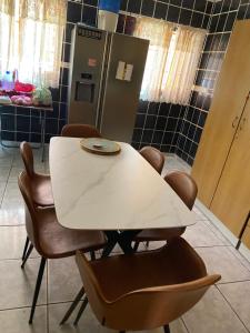 a white table and chairs in a kitchen with a refrigerator at Alvin ‘s House in Tsumeb