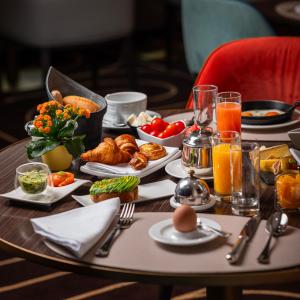 una mesa cubierta con productos para el desayuno y zumo de naranja en Hotel Bristol, en Ginebra