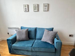 a blue couch in a living room with two pillows at The Amber Suite in Manchester +7 photos