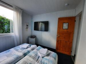 a bedroom with two beds and a tv and a door at Ferienhaus "Auszeit mit Herz" im Ferienpark Extertal - Kamin, Fass-Sauna, Massagesessel in Extertal