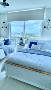a white bedroom with two beds and a large window at Exclusivo, Moderno y Cómodo Apto temático con hermosa Vista al Mar in Playa Blanca