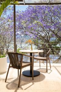 een tafel en stoelen op een patio met paarse bloemen bij El Santuario Resort & Spa in Valle de Bravo