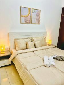 Cozy 2 Bedroom Apartment in Al Nahda Dubai في دبي: سرير كبير في غرفة النوم ومصباحين