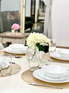 un tavolo con piatti e un vaso con fiori sopra di Cozy 2 Bedroom Apartment in Al Nahda Dubai a Dubai