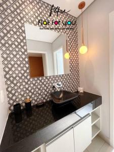 een badkamer met een wastafel en een spiegel bij 1501B - Espaçoso apê 2Q St Bueno in Goiânia