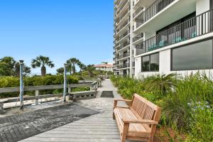 a wooden bench on a walkway next to a building at One Seagrove Place 0506 in Seagrove Beach