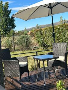 a table and chairs on a deck with an umbrella at Entre Sierras VGB Bertone in Villa General Belgrano