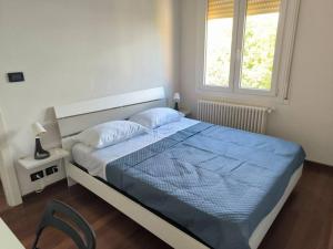 a bedroom with a bed with a blue comforter and a window at Appartamento nuovo e delizioso in Vidiciatico