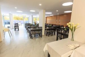 un comedor con mesas blancas, sillas y flores en HOME HOTEL SCANDINAVIA en Ulcinj