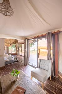a living room with a chair and a bed and window at Mopani Safari Lodge in Mfuwe