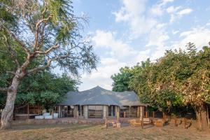 a tent with benches in front of some trees at Mopani Safari Lodge in Mfuwe