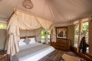 a bedroom with a canopy bed and a mirror at Mopani Safari Lodge in Mfuwe