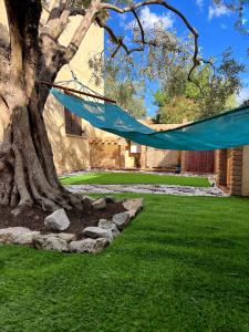 a blue hammock hanging from a tree in a yard at Casa L ulivo in Santa Maria Navarrese