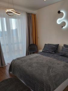 a bedroom with a bed and a chair and a window at Light Apartments in Chernihiv