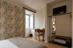 um quarto com uma cama, uma secretária e uma janela em Hotel Vitória em Coimbra