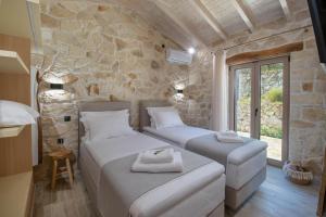 two beds in a room with a stone wall at Villa Stamateli, Antipaxos in Antípaxos +25 photos
