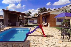a pool with a slide and an umbrella next to a house at Villa Brisa Azul in Atibaia
