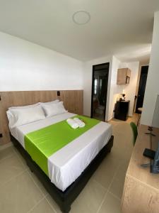a bedroom with a large bed with a green blanket at Caliview Apartahotel in Cali