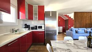 une cuisine avec des placards rouges et un salon dans l'établissement Alivia Garden, à Paliouri