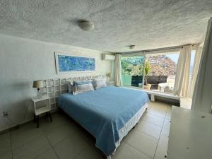 a bedroom with a blue bed and a window at Sirenas in Acapulco