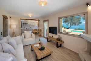 a living room with a white couch and a large window at Villa Stamateli, Antipaxos in Antípaxos