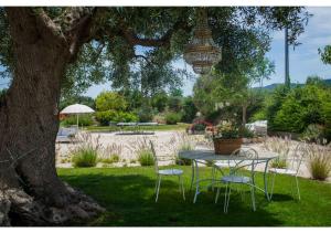 een tafel en stoelen onder een boom in een park bij Masseria Verbena suites in Macchia di Monte