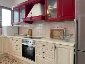een keuken met rode kasten en een fornuis met oven bij Komi Beach Condo with 3 Bedrooms in Chios