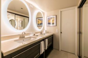a bathroom with a sink and a large mirror at Aston Waikiki Beach Tower in Honolulu