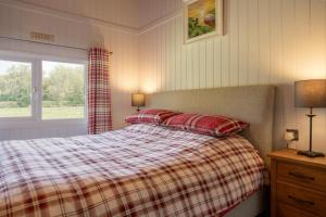 a bedroom with a bed with a plaid blanket and a window at Tesseyman Lodge in Bubwith