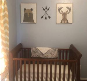 een babybedje met twee foto's van dieren aan de muur bij Charming Home in the Piney Woods of East Texas in Kilgore