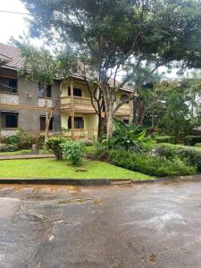 a large house with a tree in front of it at Queens apartments in Entebbe