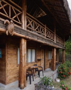 una cabaña de madera con una mesa y sillas frente a ella en Paraíso Natural Ecohotel en San Bernardo del Viento