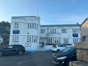 a white building with cars parked in a parking lot at The Yacht Inn in Penzance